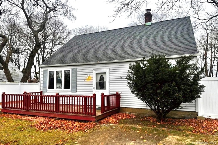 Rear view of property with a wooden deck, a shingled roof, and a chimney