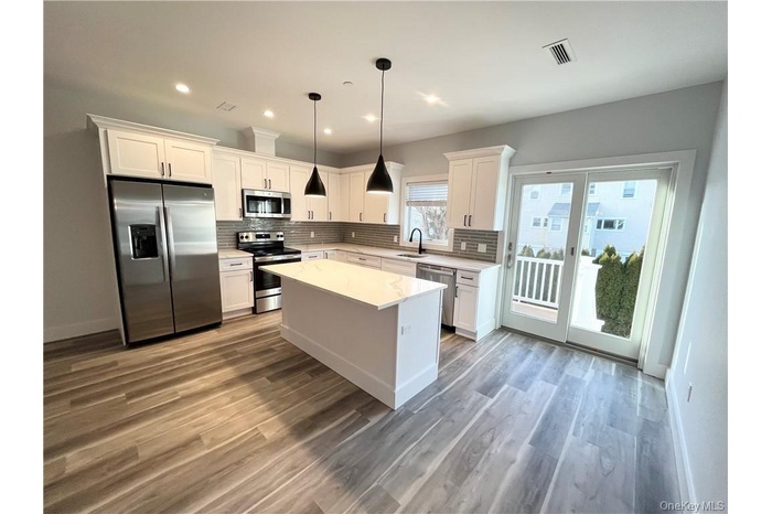 Kitchen featuring appliances with stainless steel finishes, white cabinetry, a kitchen island, and recessed lighting