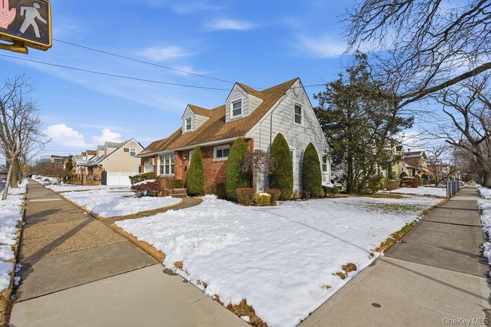 Snow covered property featuring a residential view and brick siding