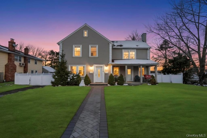 View of front facade featuring stucco siding, covered porch, and a chimney