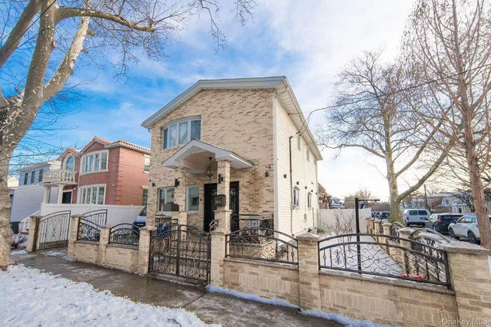 View of front of home with a gate, a fenced front yard, and brick siding