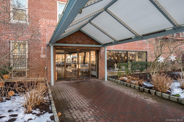 Snow covered property entrance featuring brick siding and a patio area