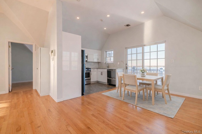 Dining room with light wood-style floors, recessed lighting, and high vaulted ceiling