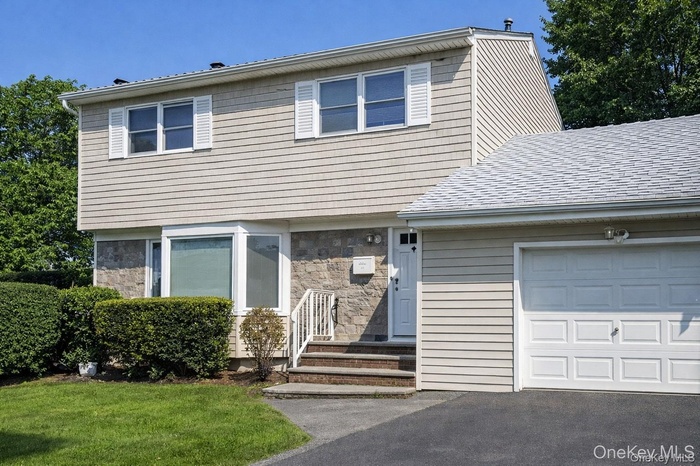 Colonial home with stone siding and an attached garage