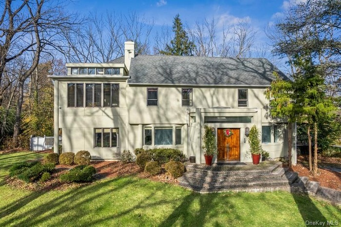 View of front of home with a front lawn, a chimney, and stucco siding