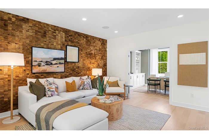 Living room with an accent wall, wood finished floors, and recessed lighting
