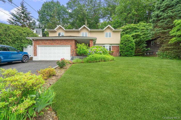 View of front of home featuring brick siding, asphalt driveway, a front lawn, and a garage