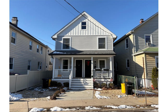 American foursquare style home with board and batten siding and a porch