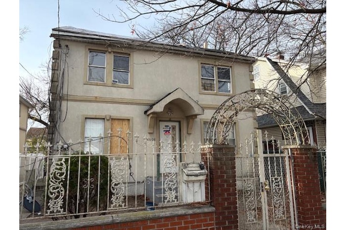 View of front facade with stucco siding, a fenced front yard, and a gate