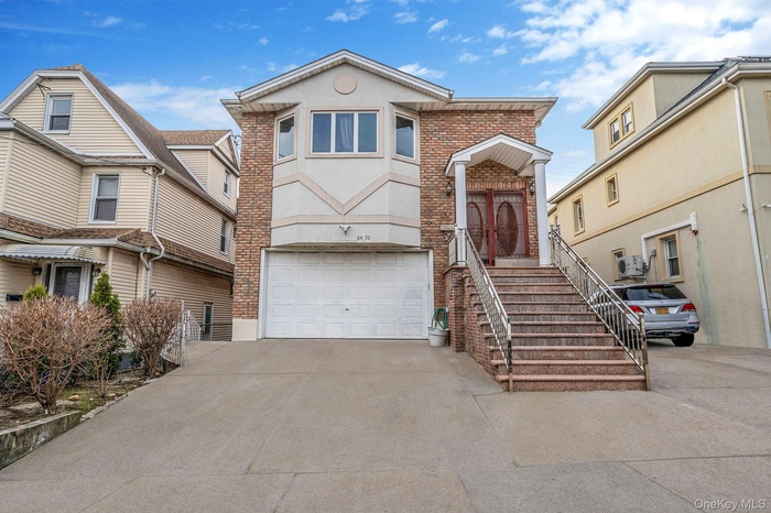 View of front of property with brick siding, driveway, stucco siding, and a garage