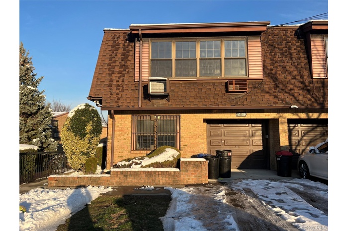 View of front of house with roof with shingles, brick siding, and a garage