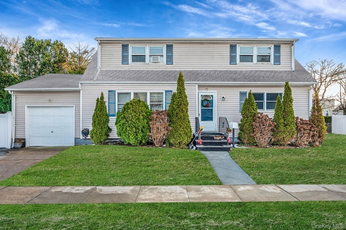 Traditional home featuring a garage, concrete driveway, and roof with shingles