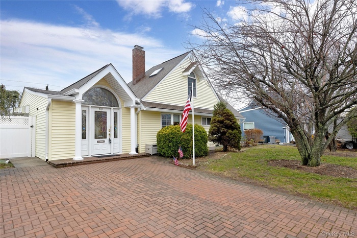 View of front of home with a chimney, roof with shingles, and a front lawn