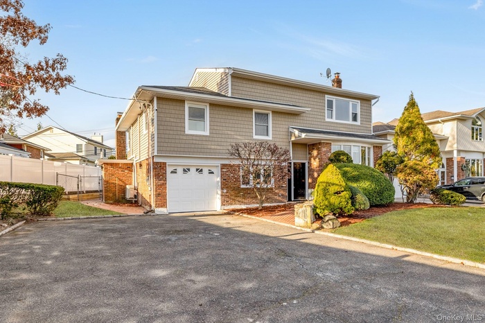 View of front of home featuring a chimney, brick siding, an attached garage, and asphalt driveway