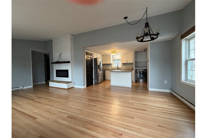 Kitchen featuring open floor plan, a chandelier, stainless steel refrigerator with ice dispenser, washer / dryer, and a fireplace