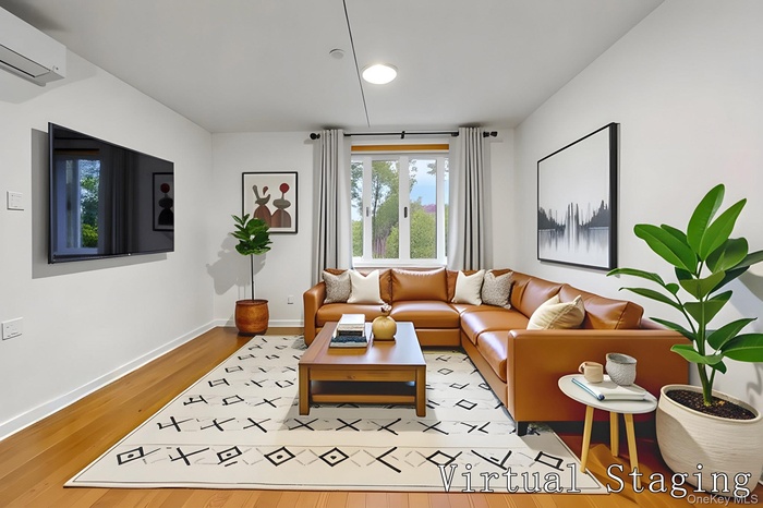 Living area featuring a wall mounted air conditioner and light wood finished floors