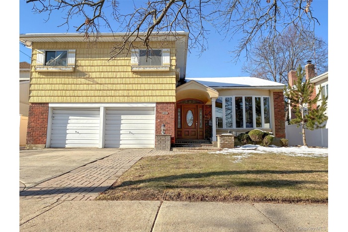 View of front of house with brick siding, concrete driveway, a garage, and a front lawn