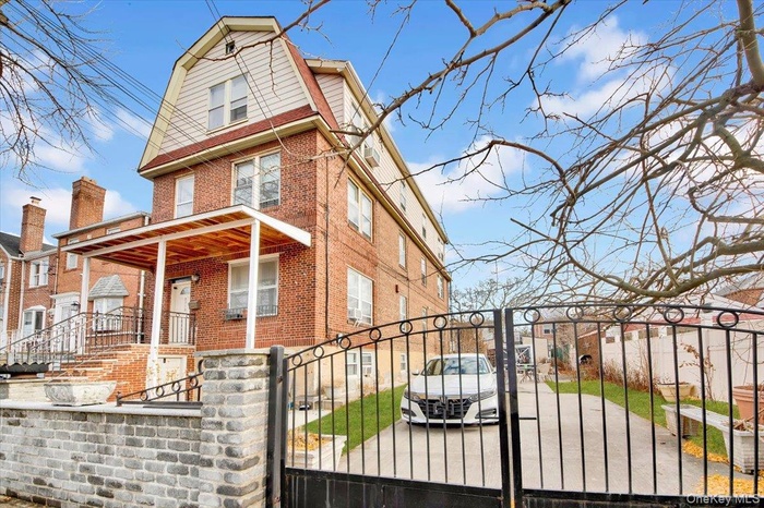 View of front of house featuring a gambrel roof, brick siding, a gate, a fenced front yard, and a residential view