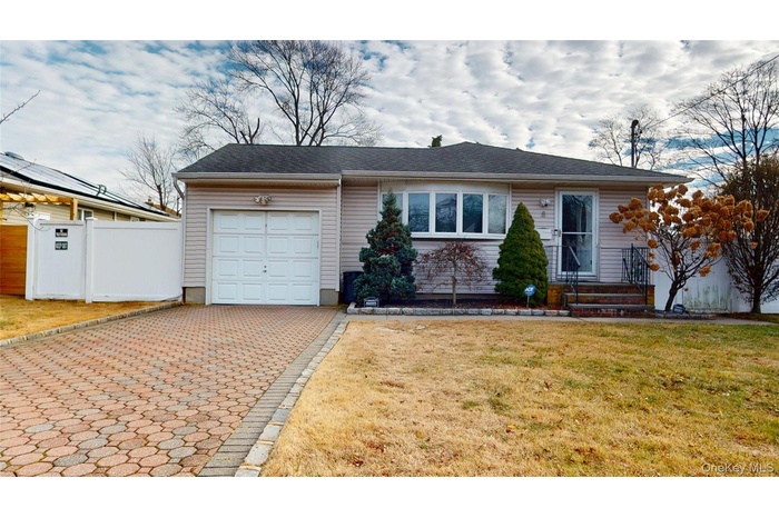 Ranch-style home featuring decorative driveway, a garage, and roof with shingles