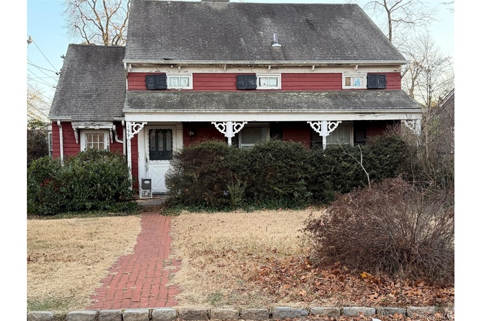 View of front of property featuring a chimney and a shingled roof