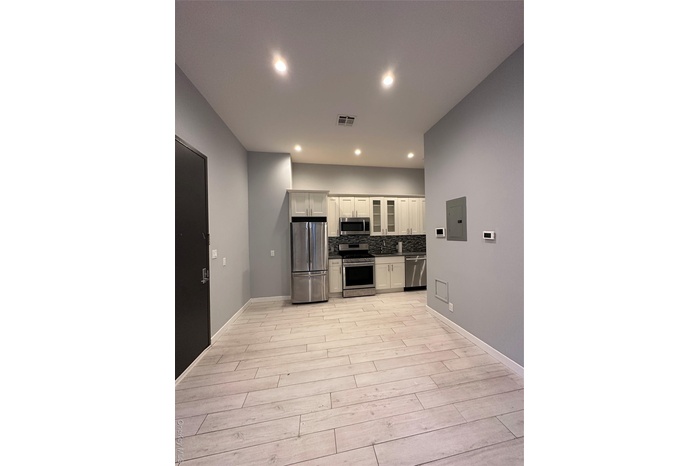 Kitchen featuring white cabinets, appliances with stainless steel finishes, glass insert cabinets, electric panel, and recessed lighting
