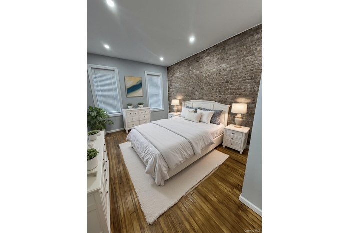 Bedroom with dark wood-type flooring, recessed lighting, and an accent wall