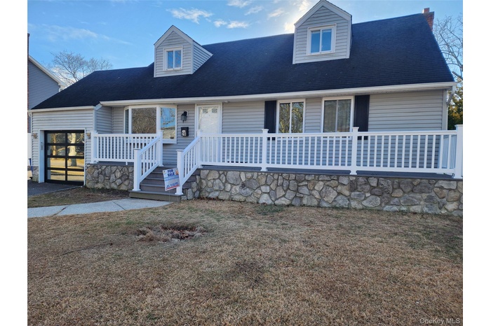 New england style home featuring roof with shingles, a garage, and a front yard