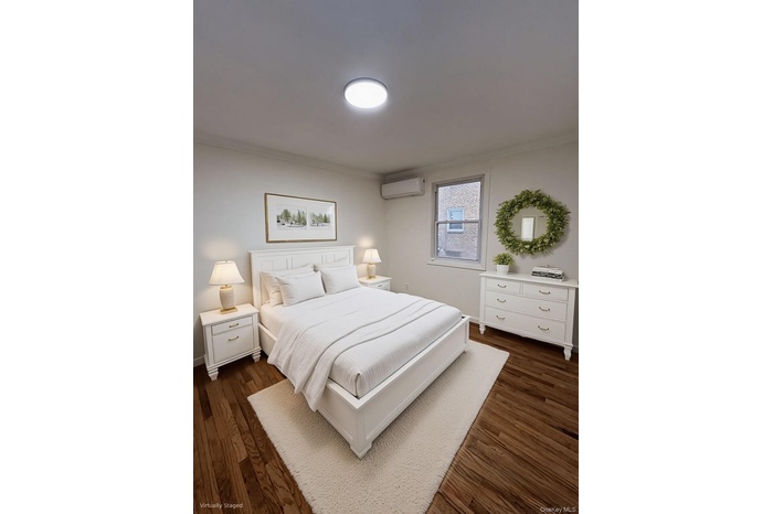 Bedroom with ornamental molding, dark wood-style floors, and a wall unit AC