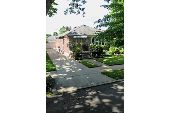 View of front of home with brick siding, a chimney, and a front lawn