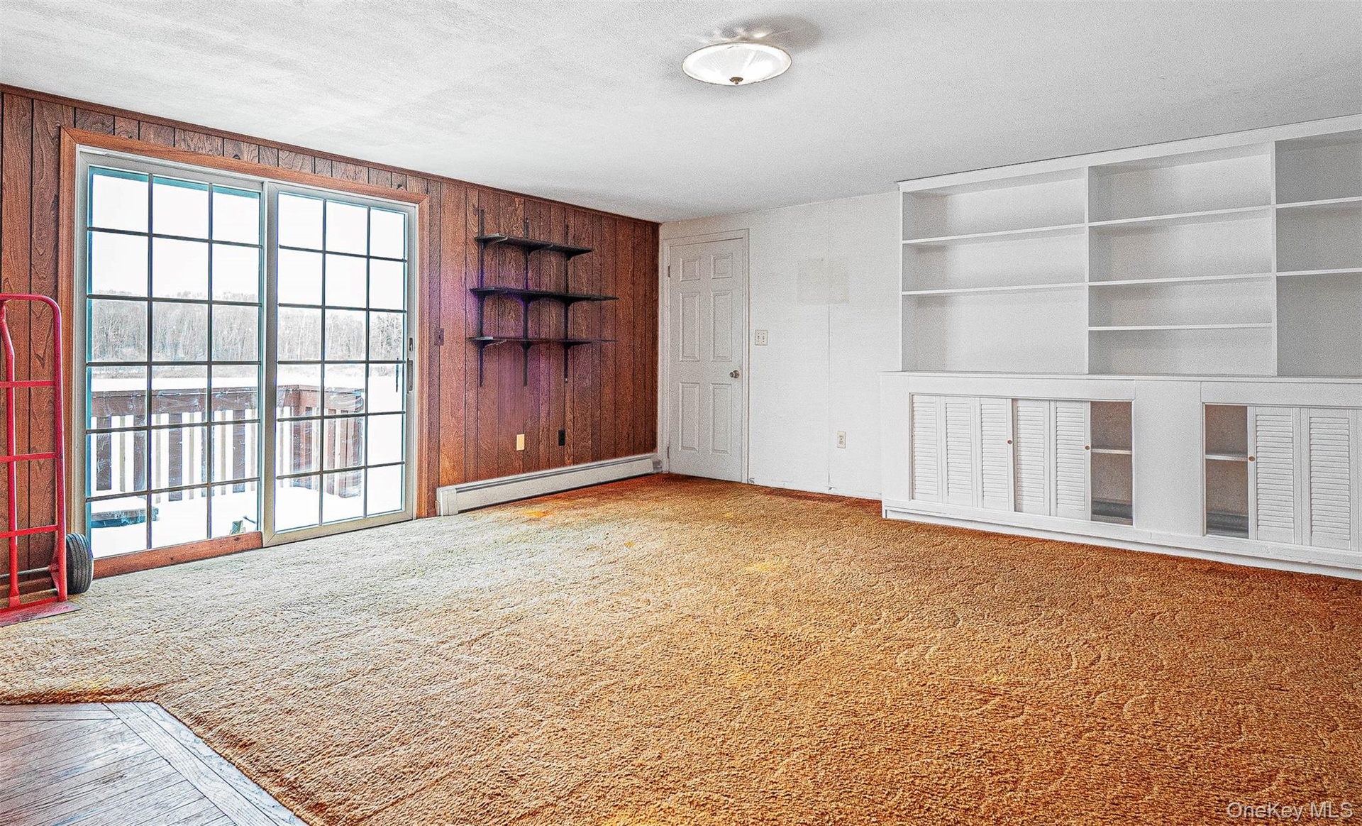 Family room with built in features, wet bar, light carpet, a baseboard radiator, a textured ceiling, and wooden walls