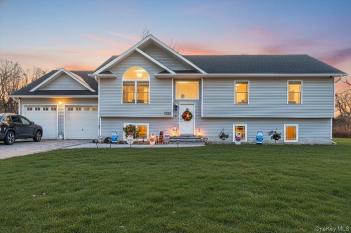 Split foyer home featuring driveway, a lawn, an attached garage, and a shingled roof
