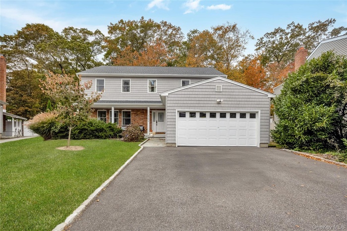 Traditional home featuring a porch, a front yard, driveway, and an attached garage