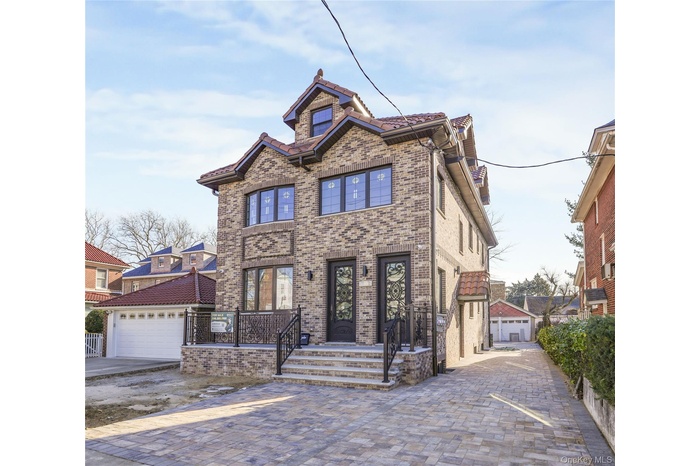 View of front of property with brick siding, an outbuilding, and a garage