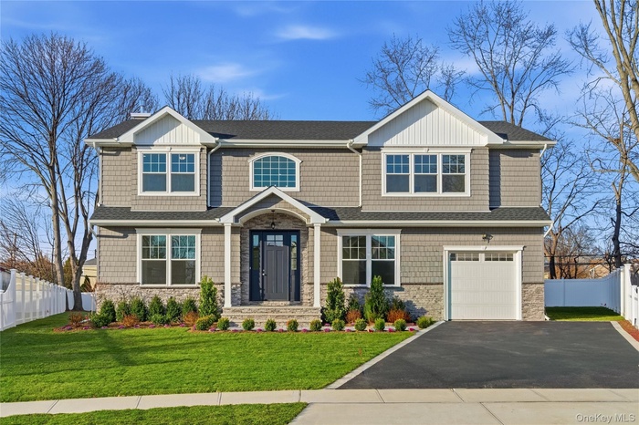 View of front of home featuring stone siding, asphalt driveway, a shingled roof, and an attached garage