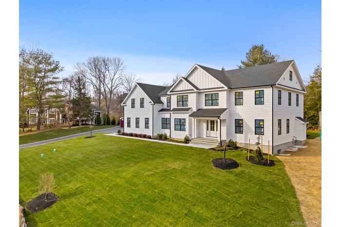 Modern farmhouse style home with board and batten siding, a front lawn and covered porch