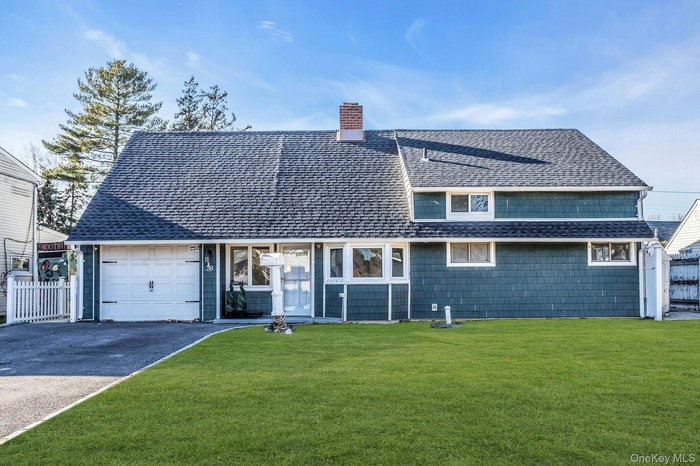 View of front of house with roof with shingles, driveway, a chimney, and an attached garage