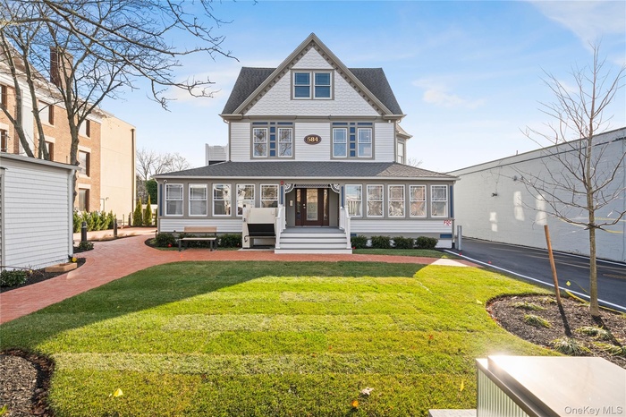 Victorian home featuring a shingled roof and a front yard