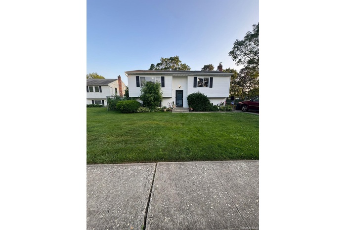 Split foyer home with a front yard and a chimney