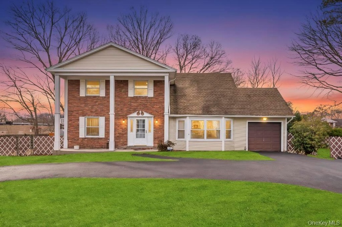 Greek revival inspired property featuring driveway, a garage, brick siding, and covered porch
