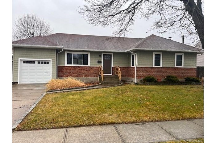 Single story home with a garage, a front lawn, roof with shingles, and concrete driveway
