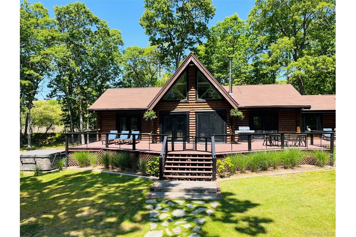 Log home featuring log siding, a front lawn, and a wooden deck