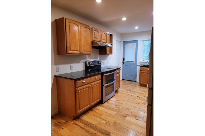 Kitchen featuring stainless steel electric range oven, extractor fan, light wood-style flooring, recessed lighting, and fridge