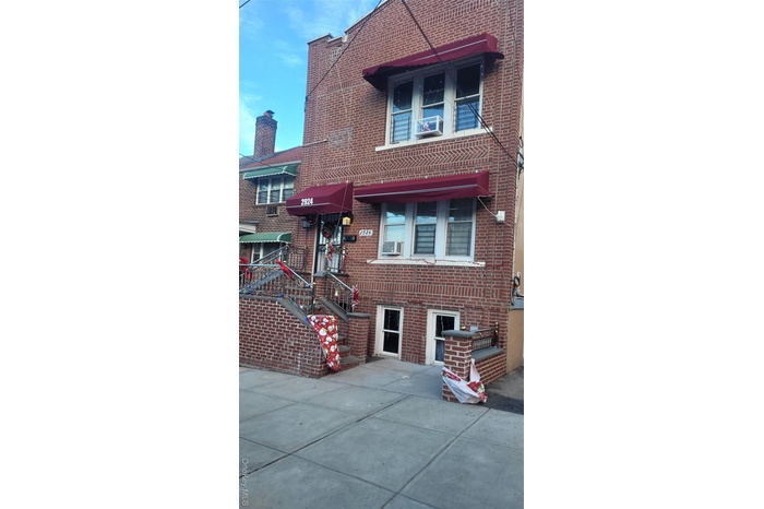View of front of house with brick siding and a balcony