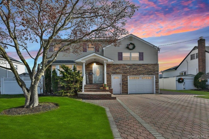 View of front of home featuring decorative driveway, stone siding, a garage, and a gate