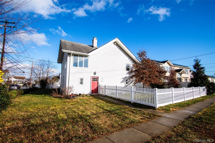View of side of property featuring a fenced front yard and a chimney