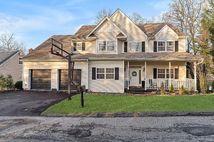 View of front of house with asphalt driveway, a porch, a front yard, and an attached garage