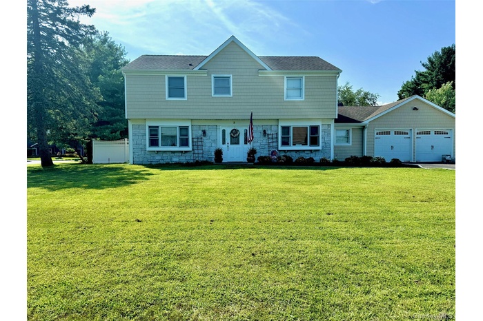 Colonial house with stone siding, roof with shingles, and an attached garage
