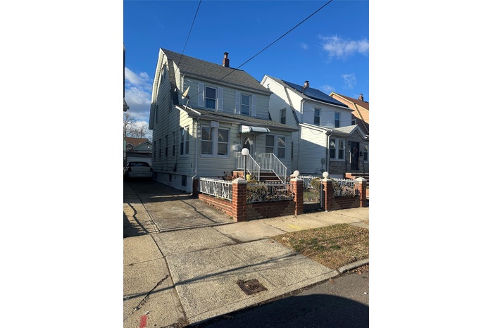 View of front of house featuring a chimney, a fenced front yard, and a gate