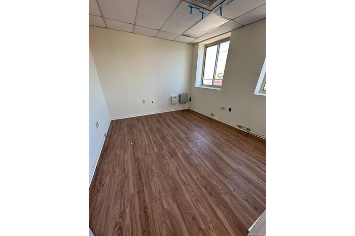 Unfurnished room with wood finished floors and a drop ceiling