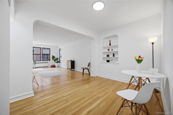 Sitting room with built in shelves, light wood-style flooring, and arched walkways